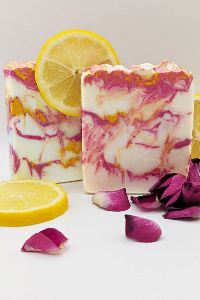 Marbled soap bars with lemon slices and purple petals on a white background